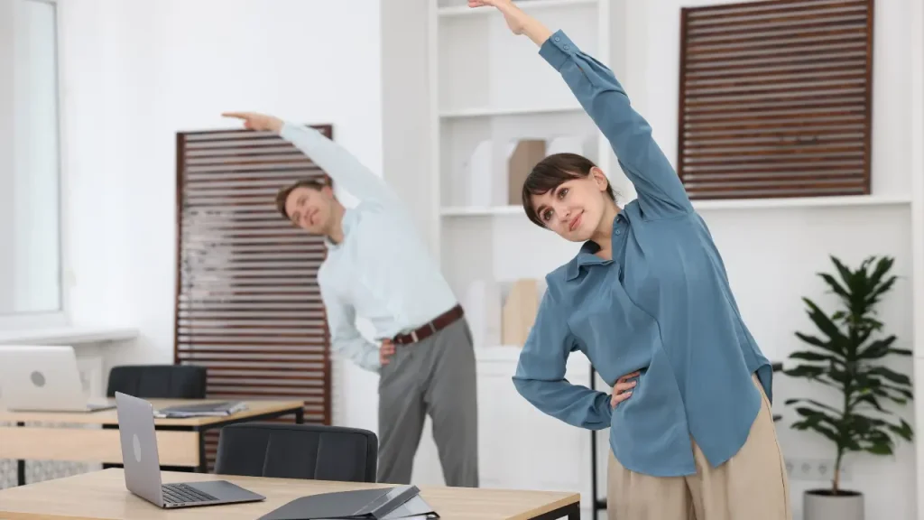 Mulher de blusa azul e homem de blusa social branca fazendo exercícios de mobilidade em sala de descompressão
